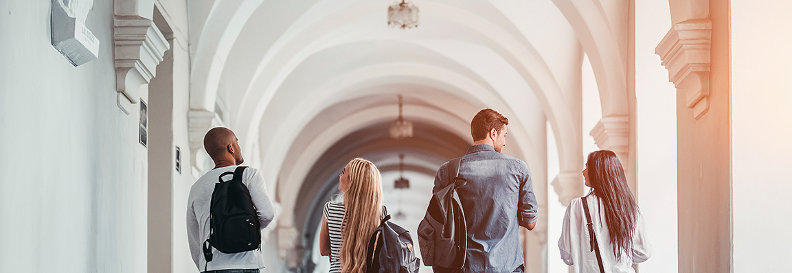 Beca en certificado americano; jovenes universitarios en un pasillo con arcos